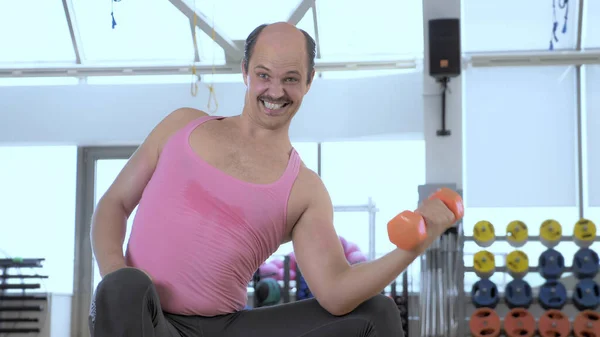 Orta boy. Kel komik adam spor salonunda dambıllarla antrenman yapıyor. — Stok fotoğraf