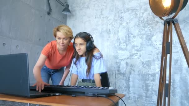 Mulher e menina jogando teclado midi e laptop juntos em estúdio — Vídeo de Stock