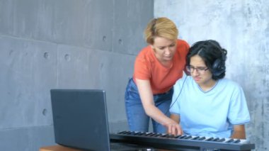 Stüdyoda birlikte çalan kadın ve çocuk midi klavye ve dizüstü bilgisayarla