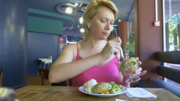 Een vrouw die vegetarisch eten eet in een café. kopieerruimte — Stockvideo