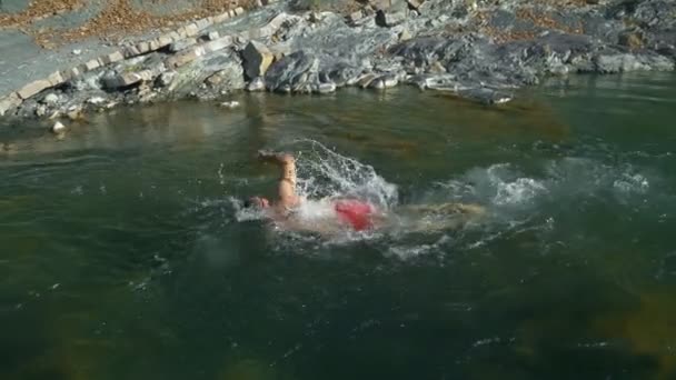 Een man zwemt borstslag in de rivier tegen de stroom in — Stockvideo