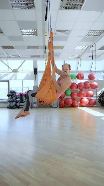 Vertically. cheerful, smiling balding man in a hammock for aerial yoga classes. — Stock Photo, Image