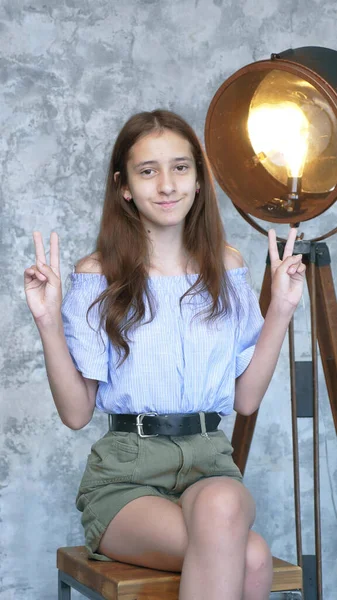 Vertikal. Nettes Teenie-Mädchen zeigt zwei Finger Geste im Studio — Stockfoto