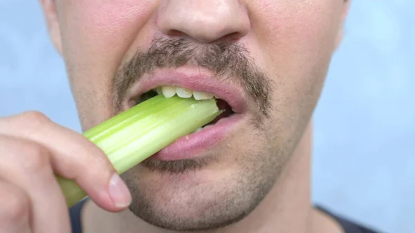 Boca de primer plano. apuesto hombre bigotudo felizmente come un tallo de apio — Foto de Stock