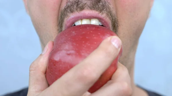 Boca fechada. um homem bigode morde uma grande maçã vermelha — Fotografia de Stock