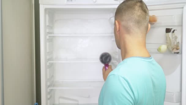 Mężczyzna rozmraża lodówkę suszarką do włosów. przygody dziwnych ludzi — Wideo stockowe