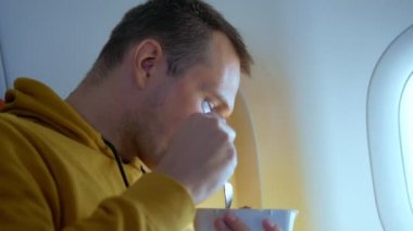 Uçakta arka planda yemek yiyen bir adam var.