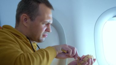 Uçakta arka planda yemek yiyen bir adam var.