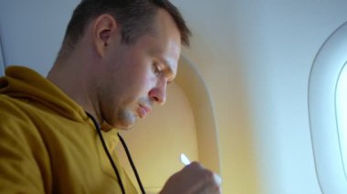 Uçakta arka planda yemek yiyen bir adam var.