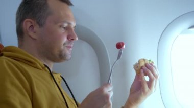 Uçakta arka planda yemek yiyen bir adam var.