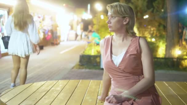 Belle femme aux yeux bleus est triste assis sur une soirée d'été dans le parc — Video