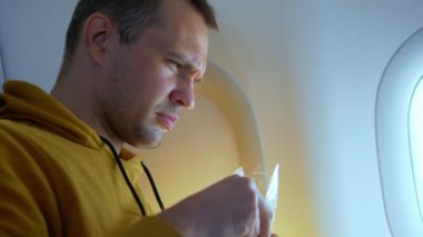 Uçakta arka planda yemek yiyen bir adam var.