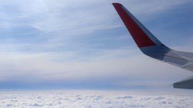 Bulutların ve gökyüzünün arka planına karşı havada bir uçak kanadı. Boşluğu kopyala