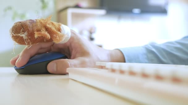 Bandajlı parmaklı bir adamın eli bilgisayar faresi ve klavye kullanıyor. — Stok video