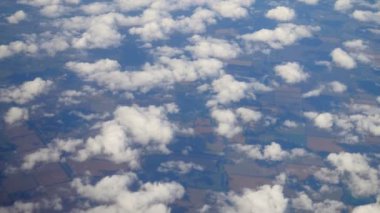 Uçan bir uçaktan yere beyaz bulutların arasından görünen manzara. Boşluğu kopyala