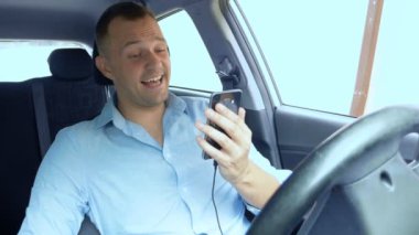 Araba kullanırken akıllı telefon kullanan ve gülen bir gencin portresi.