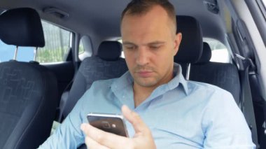 Araba kullanırken akıllı telefon kullanan ve gülen bir gencin portresi.