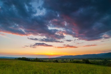Yeşil bir alan üzerinde renkli ve dramatik gün batımı