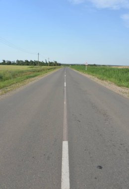 paved road through green fields and hills in summer