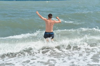 Denizdeki ortalama dalgalar kıyıya köpükle ulaşır ve bir gürültüyle kayalara çarpar.