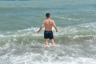 Denizdeki ortalama dalgalar kıyıya köpükle ulaşır ve bir gürültüyle kayalara çarpar.