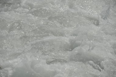 Denizdeki ortalama dalgalar kıyıya köpükle ulaşır ve bir gürültüyle kayalara çarpar.