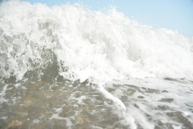 Denizdeki ortalama dalgalar kıyıya köpükle ulaşır ve bir gürültüyle kayalara çarpar.