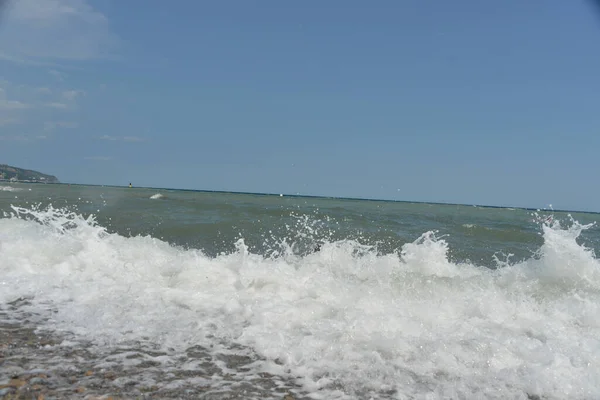 海面上的平均海浪带着泡沫到达海岸 并以噪音撞击岩石 — 图库照片