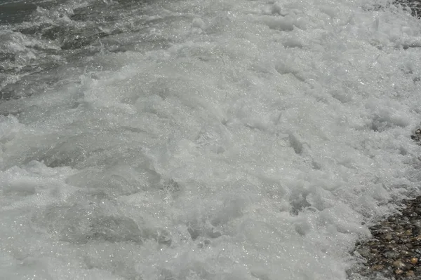海の平均波は泡で岸に到達し騒音で岩に衝突します — ストック写真