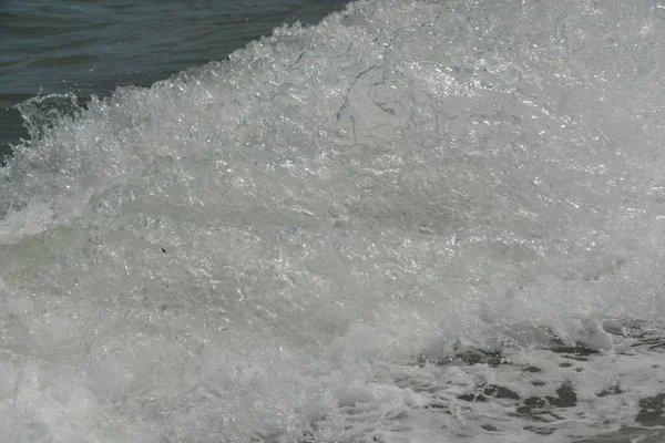 海面上的平均海浪带着泡沫到达海岸 并以噪音撞击岩石 — 图库照片