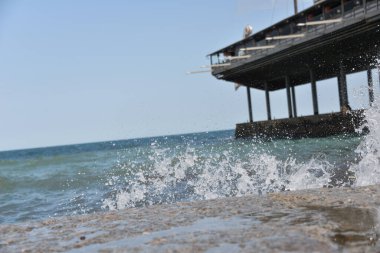 Gün boyunca deniz dalgaları ve küçük damlalar sahile düşer.