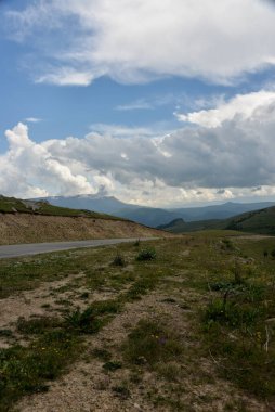 Yol yatağı düzensiz, sarmal, dağların ve kayalıkların arasından geçiyor. Bulutlar karanlık, alçak ve yağmurlu. Yol boyunca yoğun beyaz bir sis yayılıyor..