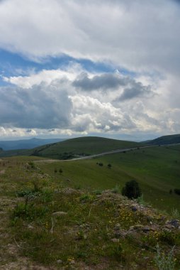 Yol yatağı düzensiz, sarmal, dağların ve kayalıkların arasından geçiyor. Bulutlar karanlık, alçak ve yağmurlu. Yol boyunca yoğun beyaz bir sis yayılıyor..