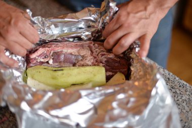 Bir sonbahar günü evdeki ızgarada kendi ellerinle folyoya sarılı et pişirme süreci.