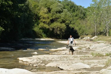 Sonbaharda sıcak bir günde köpekli bir adam nehir boyunca yürür.