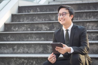 Gülümseyen Asyalı adamın portresi bilgisayar tableti kullanarak kendinden emin görünüyor