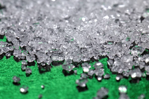 White sugar crystals on a dark green background — Stock Photo, Image