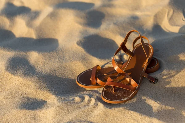 Elegant brown women's sandals on the sand
