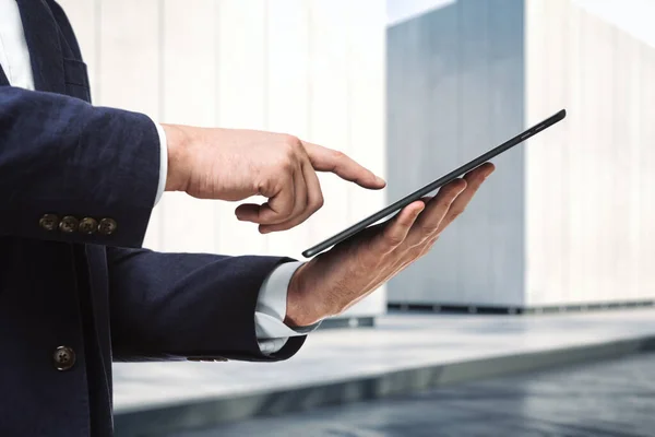 Hombre presiona en la pantalla de una tableta digital cerca del exterior del centro de negocios en un día soleado, de cerca. Concepto de tecnología online — Foto de Stock
