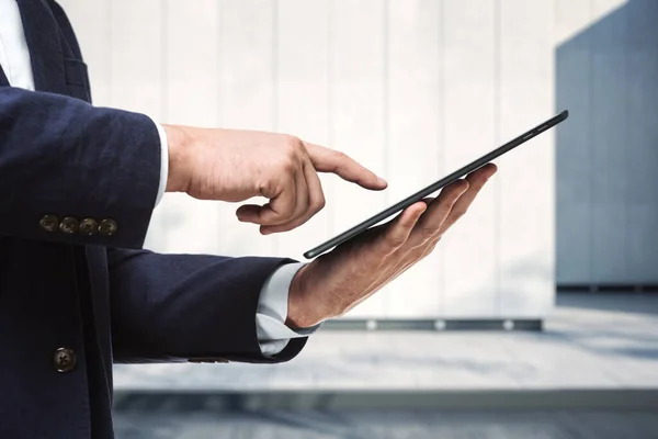 Hombre presiona en la pantalla de una tableta digital cerca del exterior del centro de negocios en un día soleado, de cerca. Concepto de tecnología online — Foto de Stock