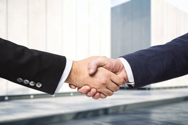 ビジネスセンターの日当たりの良い外観を背景に2人のビジネスマンの握手、契約の概念の署名、クローズアップ — ストック写真