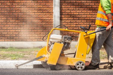 Açık çalışma: asfalt yol kesmek için makine kullanarak çalışan. Yeni bir yol inşa süreci