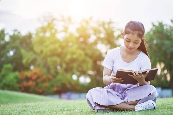 Güzel Asyalı kız ya da öğrencilerin genel parkta bir kitap okuma. Eğitim veya kullanılan kavram sakin ol