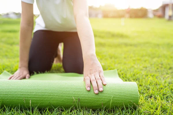 Asya yeşil yoga mat tutan güzel ve yoga egzersizleri Park yapmak için hazırlamak. Relax ve sağlıklı kavramı için kullanılan
