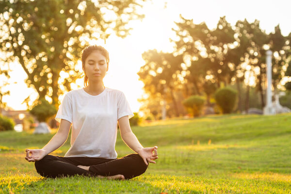 Pretty asian woman doing yoga exercises in the park. Used for relax and healthy concept