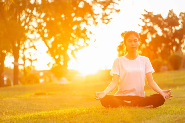 Güzel Asyalı kadın parkta günbatımı objektif parlama efektli Yoga egzersizleri yapıyor. Relax ve sağlıklı kavramı için kullanılan