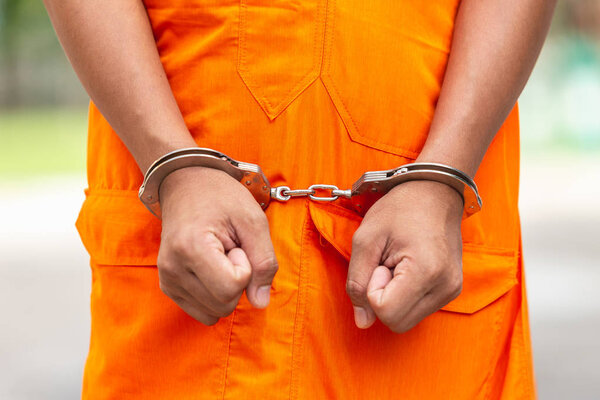 Close up arms of Thai monk with metal silver handcuff. Arrest the monk or criminal concept