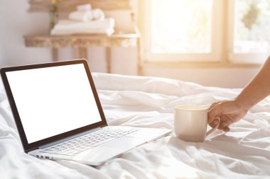 Kahve fincanı ve laptop yatağa sabah zamanında, odak el üstünde tutan el kadar kapatın