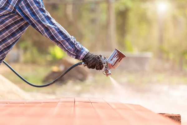 Arbeiter sprüht Farbe auf Stahlrohr, um den Rost auf dem Stahlrohr zu verhindern — Stockfoto