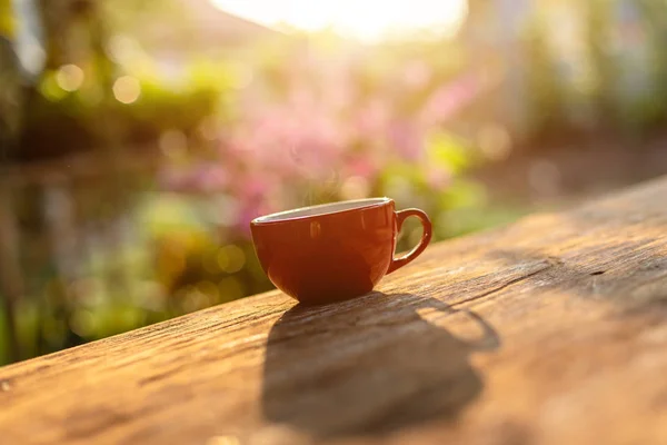 Taza de café rojo sobre mesa de madera luz de la naturaleza de la mañana en el jardín co —  Fotos de Stock